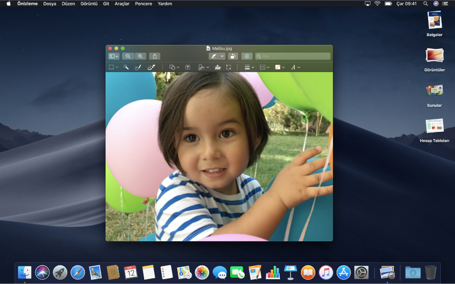 Koyu görünen bir uygulama penceresi, Dock ve menü çubuğunu gösteren, koyu görünüme ayarlanmış bir Mac masaüstü.