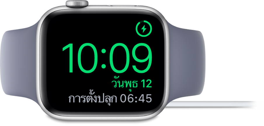 Apple Watch ที่วางตะแคง และเชื่อมต่ออยู่กับที่ชาร์จ โดยหน้าจอแสดงสัญลักษณ์การชาร์จตรงมุมขวาบนสุด เวลาปัจจุบันอยู่ด้านล่างสัญลักษณ์การชาร์จ และเวลาของการตั้งปลุกครั้งต่อไป