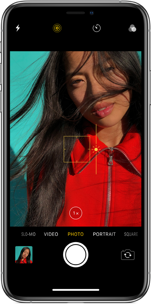 The Camera screen in Photo mode. In the viewer, an outline of a yellow box shows the area of focus, and a slider can be dragged up or down to adjust the exposure. The 1x Zoom button can be used to zoom in.