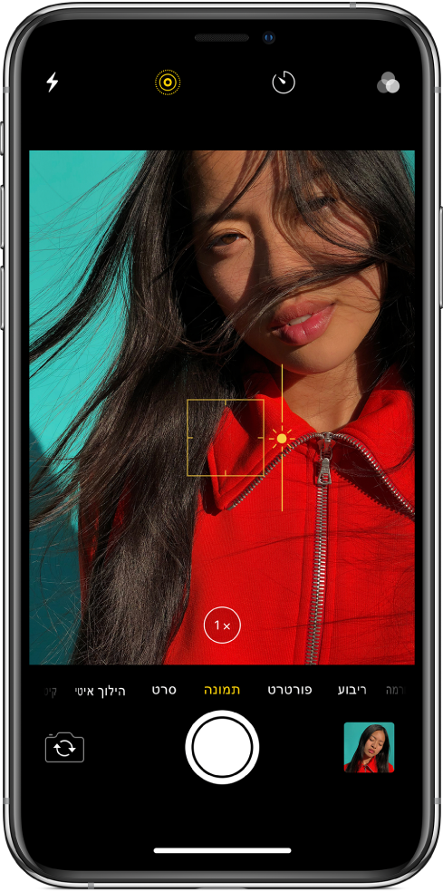 מסך ״מצלמה״ במצב ״תמונה״. בעינית ניתן לראות קו מתאר של תיבה צהובה המציג את אזור המיקוד ומחוון שניתן לגרור מעלה ומטה כדי לכוונן את החשיפה. בכפתור של זום פי 1 ניתן להשתמש כדי להגדיל.