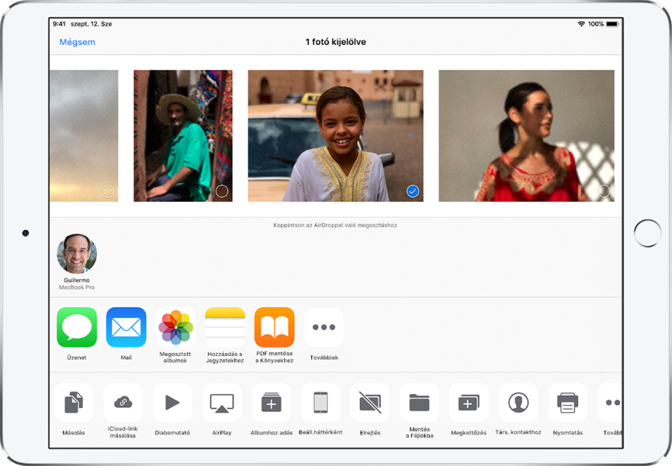 A megosztási képernyő, amelynek tetején fotók láthatók. A fotók közül egy van kijelölve, amelyet egy kék körben lévő fehér pipa jelez. A fotók alatti sorban azok a barátok jelennek meg, akikkel fotókat oszthat meg az AirDropon keresztül. A barátok alatt további megosztási lehetőségek láthatók, amelyek balról jobbra haladva a következők: Üzenetek, Mail, Megosztott albumok, Hozzáadás a Jegyzetekhez, PDF mentése a Könyvekhez stb. Az alsó sorban lévő gombok a következők: Másolás, Mentés a Fájlokba, iCloud-link másolása, Diabemutató, AirPlay, Albumhoz adás, Beállítás háttérként, Elrejtés, Megkettőzés, Társítás kontakthoz, Nyomtatás és Továbbiak.