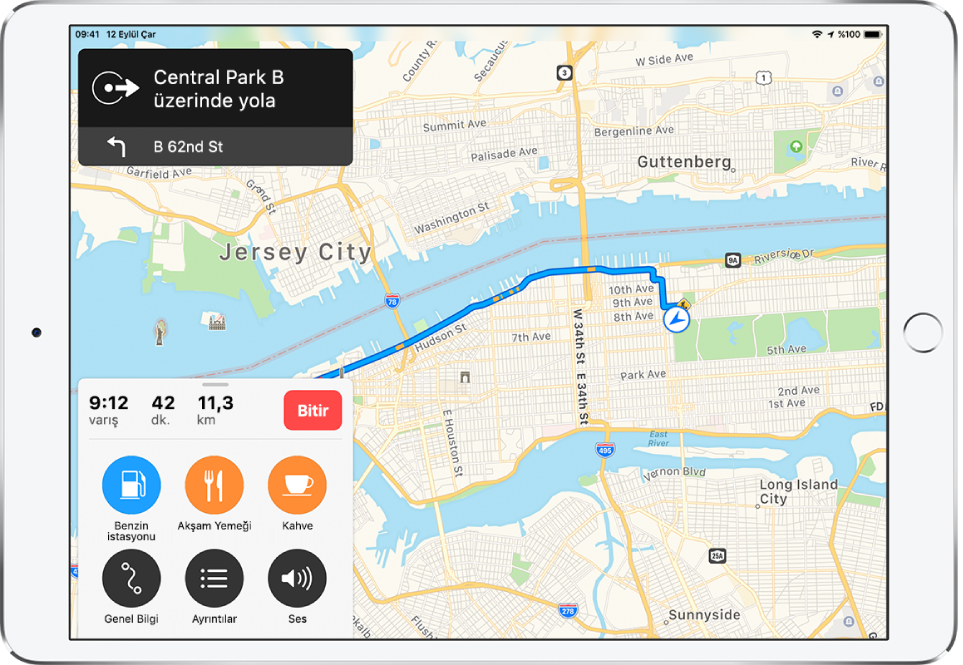 New York City’nin yol tarihini gösteren bir yol haritası Sol üst taraftaki bir başlık, Central Park West’ten başlayan ve daha sonra 62. Street’ten batıya dönme talimatı veren yol tarifi veriyor. Sol alt taraftaki bir kart, 11,3 millik bir mesafe için 42 dakikalık bir sürüş ile tahmini varışı saatini 9:12 olarak gösteriyor. Kartın üstünde, navigasyonu durdurmak için üzerinde Bitir yazan bir düğme bulunur. Kartın üstünde, üzerinde Benzin İstasyonları, Akşam Yemeği, Kahve, Genel Bilgi, Ayrıntılar ve Ses yazan düğmeler de bulunur.