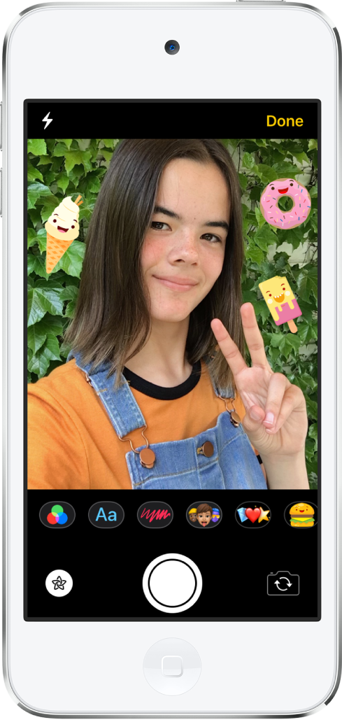 Der Nachrichten-Bildschirm für Effekte. Der obere Teil des Bildschirms zeigt die Bildansicht der Frontkamera. Im Bild befinden sich iMessage-Sticker um das Motiv herum. Unter dem Bild befinden sich, von links nach rechts, die Tasten für Filter, Text, Formen, Memoji und Animoji. Unten auf dem Bildschirm sind von links nach rechts die Tasten für Effekte, Auslöser und Kameraauswahl.