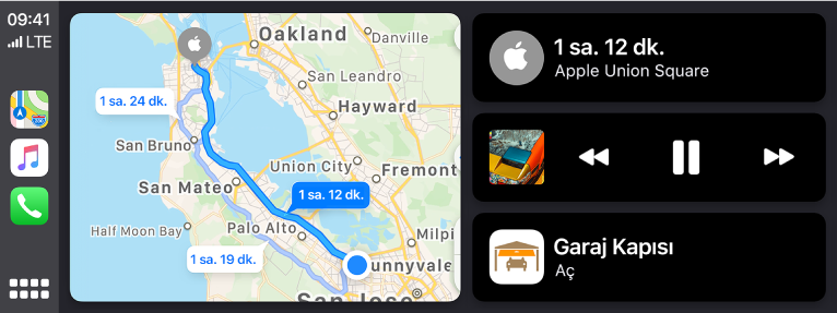 Solda Harita, Müzik ve Telefon için simgelerin, ortada araba sürme güzergâhının bir haritasının ve sağda üç öğenin üst üste gösterildiği CarPlay Dashboard. Sağda üstteki öğe Apple Union Square’e tahmini yolculuk süresinin 1 saat 12 dakika olduğunu gösteriyor. Sağdaki orta öüe ortam çalma denetimlerini gösteriyor. Alttaki öğe garaj kapısının açık olduğunu belirtiyor.