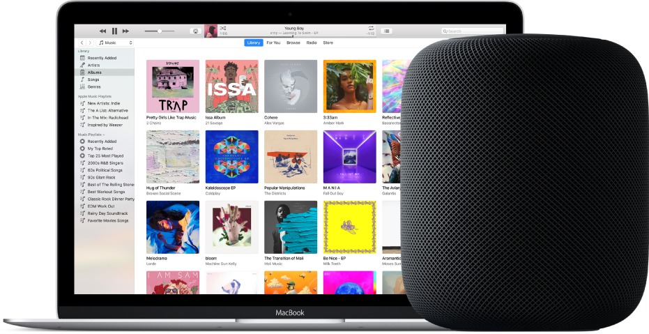A MacBook with iTunes on the screen and a HomePod nearby.