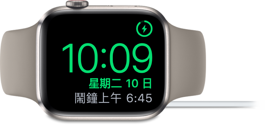 將 Apple Watch 側放並連接充電器，畫面右上角顯示充電符號，目前時間位於下方，以及下一個鬧鐘的時間。