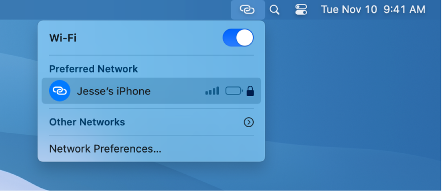 Mac datora ekrāns ar Wi-Fi izvēlni, kurā redzams Personal Hotspot savienojums ar iPhone tālruni.
