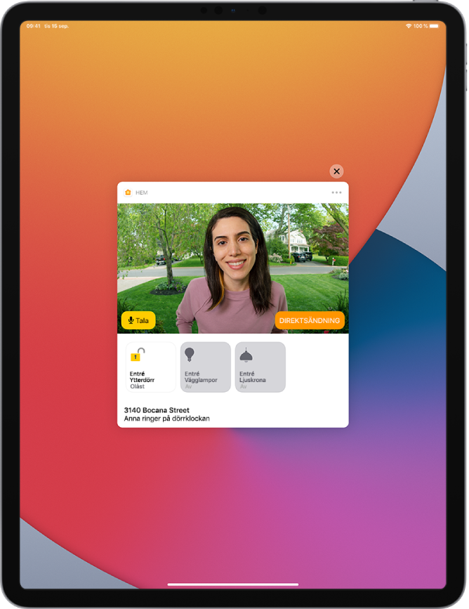 En notis från Hem visas på iPad-skärmen. Den visar bilden på en person vid ytterdörren. Till vänster finns knappen Tala. Nedanför finns tillbehörsknappar för ytterdörren och entréljus. Hemmets adress visas längst ned tillsammans med orden ”Ashley ringer på dörrklockan”. Högst upp till höger på notisen finns en stängningsknapp.