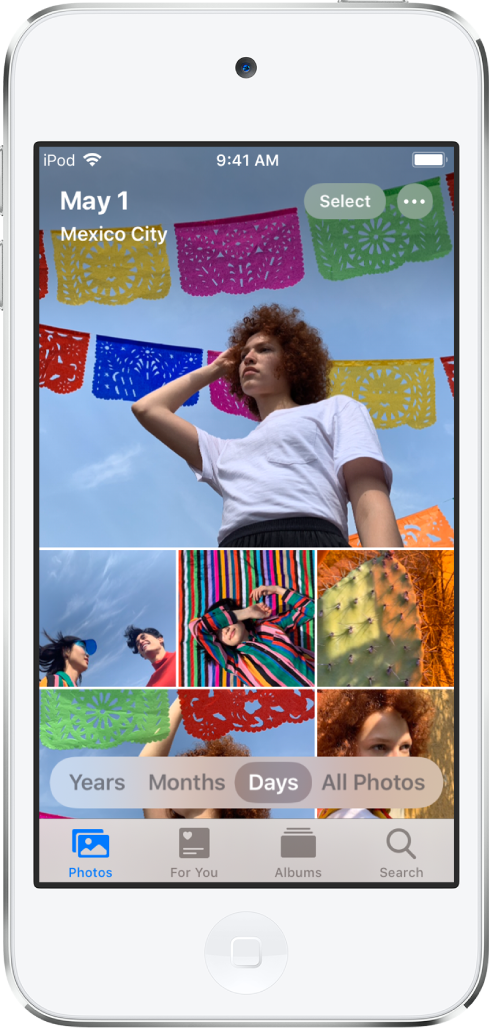 The photo library shown in Days view. A selection of photo thumbnails fills the screen. In the top left of the screen are the date and location where the photos were taken. In the top right are the Select and More Options buttons. Below the thumbnails are options to view the photo library by Years, Months, Days, and All Photos. Along the bottom are the Photos, For You, Albums, and Search tabs.