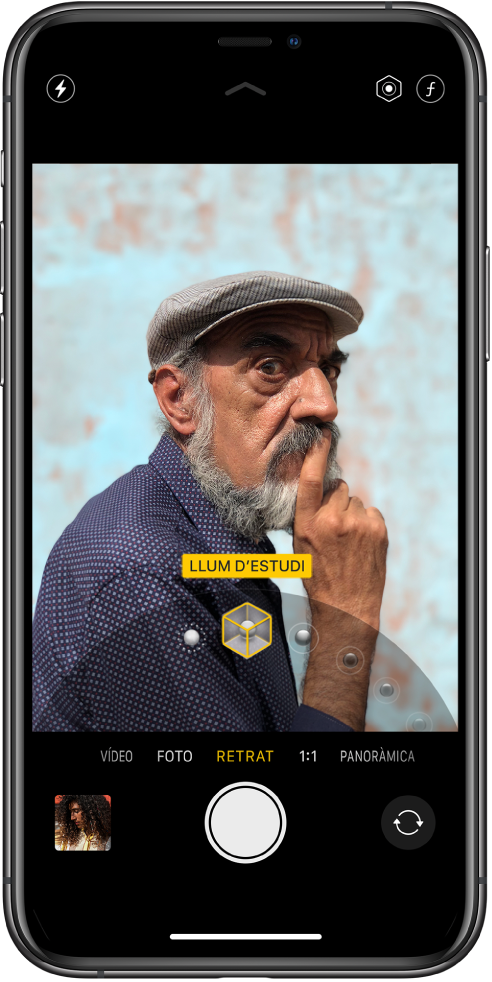 Pantalla de l’app Càmera amb el mode Retrat seleccionat. Al visor, un requadre mostra que l’opció “Il·luminació de retrat” està definida en “Llum d’estudi”, i es pot arrossegar un regulador per canviar l’opció d’il·luminació.