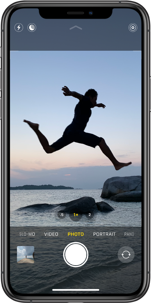 The Camera screen in Photo mode, with other modes to the left and right below the viewer. The Flash, Night mode, and Live Photo buttons are at the top of the screen. Below the camera modes are, from left to right, an image thumbnail to access photos and videos, the Shutter button, and the Switch Camera button.