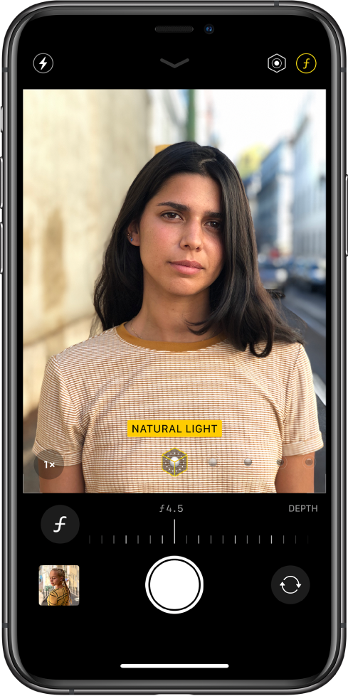 „Camera“ ekranas naudojant „Portrait“ režimą. Pasirinktas „Depth Adjustment“ mygtukas viršutiniame dešiniajame ekrano kampe. Kameros vaizdo ieškiklyje rodoma, kad „Portrait Lighting“ apšvietimo parinktis nustatyta kaip „Natural Light“ apšvietimas, o apšvietimą galite pakeisti slankikliu. Žemiau kameros vaizdo ieškiklio yra „Depth Control“ reguliavimo slankiklis.