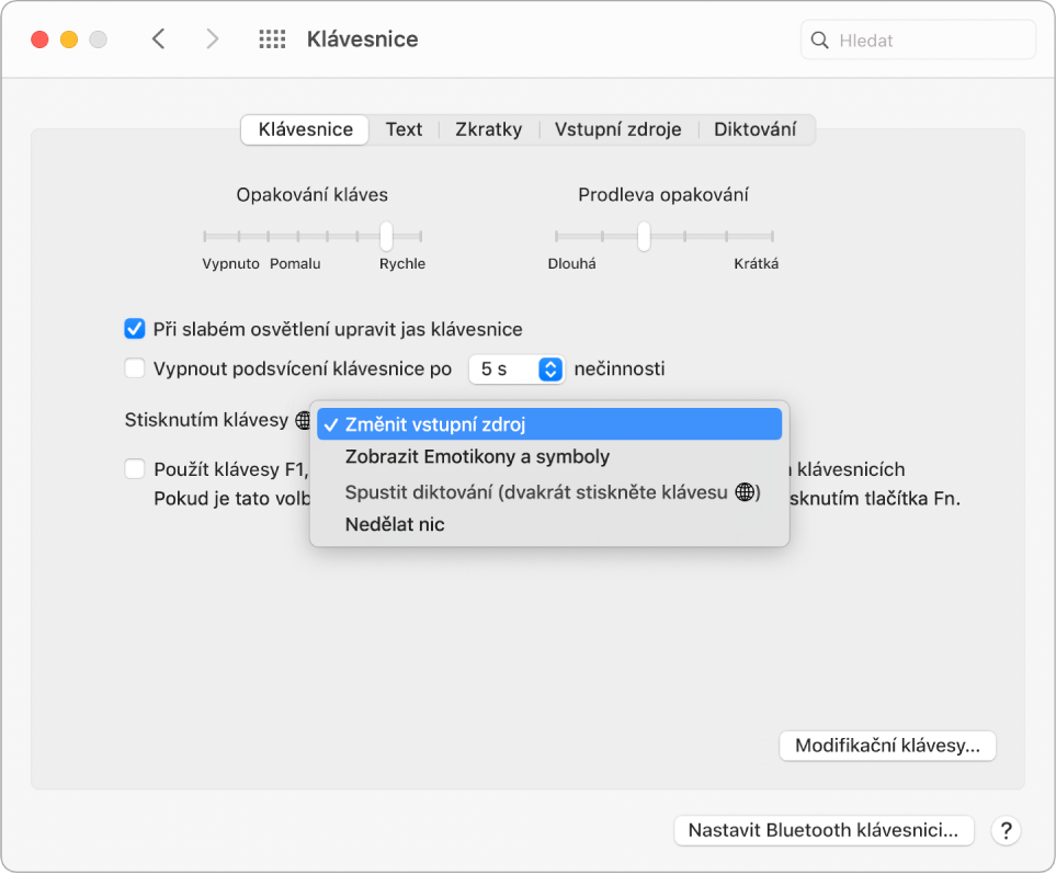 Panel předvoleb Klávesnice s rozbalovací nabídkou zobrazující volby pro funkční klávesu/klávesu s glóbem: Změnit vstupní zdroj; Zobrazit emotikony a symboly; Spustit diktování a Nedělat nic