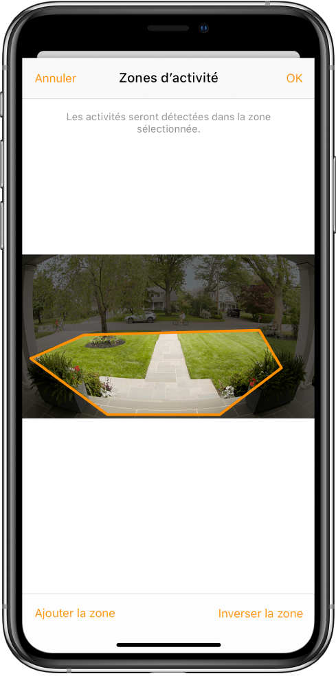 Écran d’iPhone montrant une zone d’activité dans une image prise par une caméra de porte. La zone d’activité inclut un perron et une allée, mais exclut la rue et la voie d’accès. Les boutons Annuler et OK se trouvent au-dessus de l’image. Les boutons « Ajouter la zone » et « Inverser la zone » se trouvent en dessous.