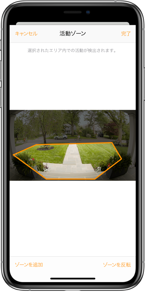 iPhoneの画面。ドアベルのカメラで撮影された画像内の活動ゾーンが表示されています。この活動ゾーンは玄関先と通路を網羅していますが、車道と私道は除外されています。画像の上には「キャンセル」ボタンと「完了」ボタンがあります。下には「ゾーンを追加」ボタンと「ゾーンを反転」ボタンがあります。