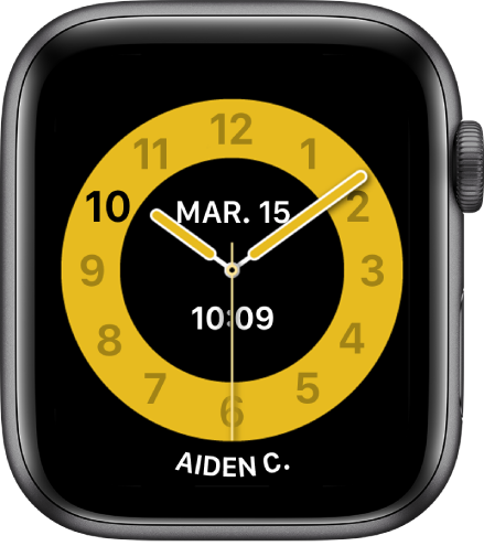 Cadran Mode École, affichant une horloge analogique avec la date vers le haut et l’heure en dessous. Le nom de la personne qui utilise l’Apple Watch se trouve en bas.