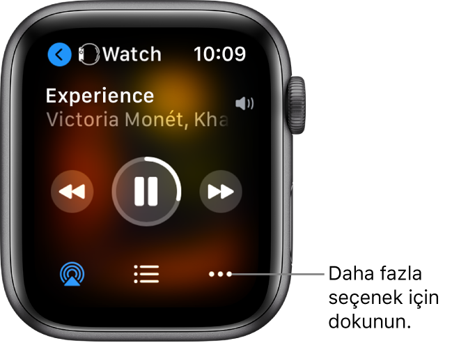 Sizi aygıt ekranına götüren solu gösteren bir ok ile üstte Watch’u gösteren Şu An Çalınan ekranı. Parça başlığı ve sanatçı adı aşağıda görünür. Çalma denetimleri ortadadır. AirPlay, parça listesi ve Daha Fazla Seçenek düğmeleri en alttadır.