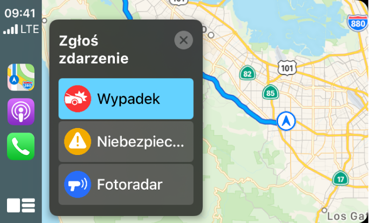 CarPlay z ikonami aplikacji Mapy, Podcasty i Telefon po lewej oraz mapą bieżącego obszaru po prawej. Widoczne są opcje zgłaszania wypadku, niebezpieczeństwa i fotoradaru.