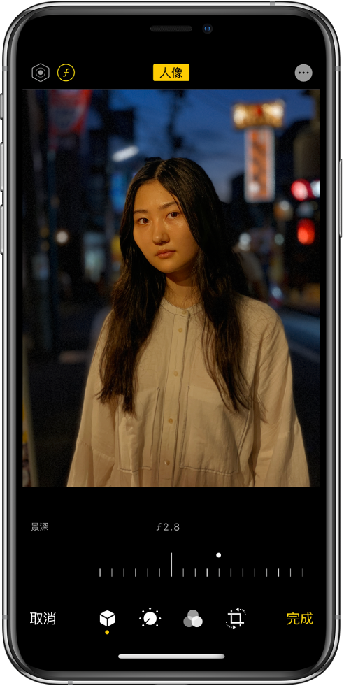 「人像」模式照片的「編輯」畫面。「光線強度」和「景深調整」按鈕位於螢幕左上角。螢幕上方中央顯示「人像」按鈕已開啟,右上角為「外掛模組」按鈕。照片位於畫面中央,照片下方的滑桿用來調整「景深調整」設定。滑桿下方由左至右分別為「取消」、「人像」、「調整」、「濾鏡」、「裁切」和「完成」按鈕。