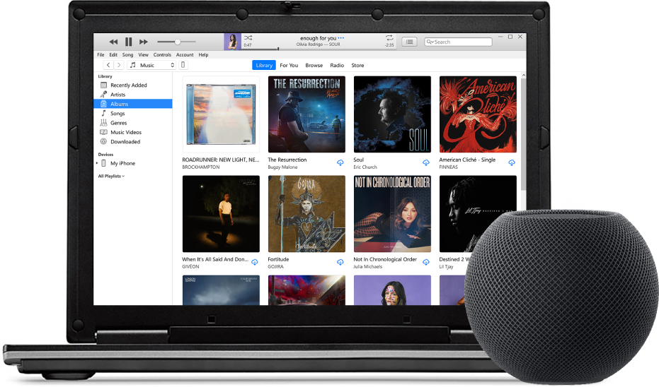 A PC with iTunes on the screen and a HomePod mini nearby.