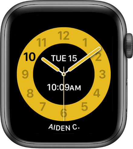 „Schooltime“ laikrodžio ciferblatas su analoginiu laikrodžiu, data ir skaitmeniniu būdu rodomu laiku arti centro. Laikrodį naudojančio asmens vardas rodomas apačioje.