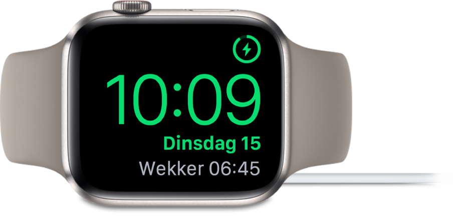 Een Apple Watch die op zijn kant ligt en is aangesloten op de oplader. Rechtsbovenin zie je het oplaadsymbool, en daaronder de actuele tijd en de tijd van de volgende wekker.