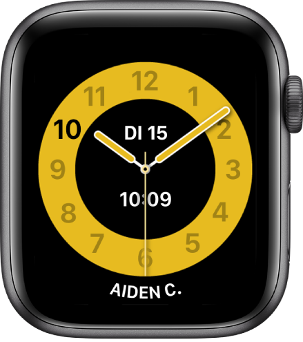 De wijzerplaat Schooltijd, waarop een analoge klok te zien is met bovenin de datum en daaronder de tijd. Onderin zie je de naam van degene die het horloge gebruikt.
