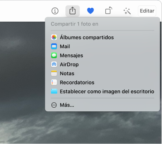 El menú Compartir, mostrado desde el botón Compartir en la barra de herramientas Fotos. El menú compartir incluye, en forma descendiente, Álbumes compartidos, Mail, Mensajes, AirDrop, Notas, Recordatorios, y “Establecer imagen del escritorio”. El último elemento es Más.