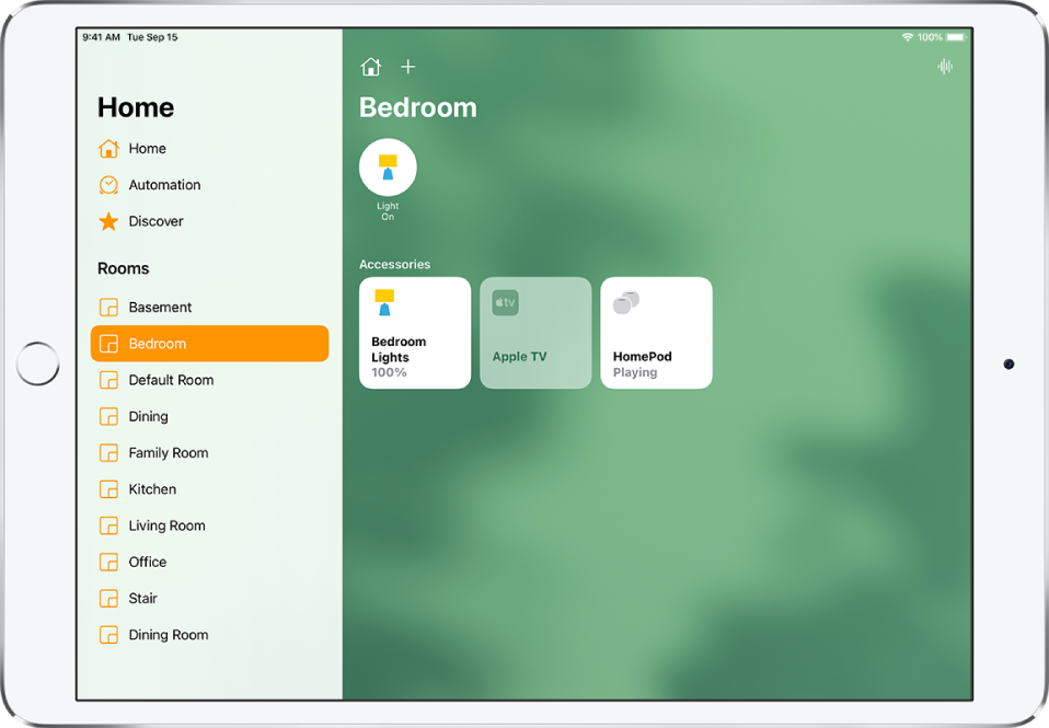 Приложението Home (Дом) със страничната лента вляво. Под Rooms (Стаи) в страничната лента е избрано Bedroom (Спалня). Вдясно от страничната лента, в горната част са бутоните Home Settings (Настройки на дома) и Add (Добави). Бутонът на домофона е горе вдясно. Близо до горния край има бутон за състоянието за осветление, показващ, че осветлението е включено. Отдолу се появяват бутони за аксесоари за осветление в спалнята, за Apple TV и за HomePod.