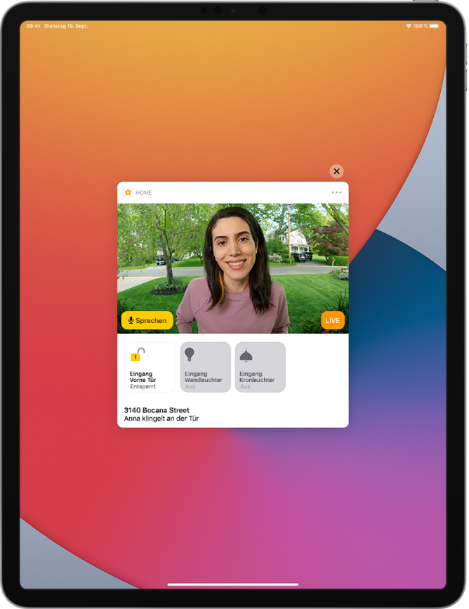 Auf dem Bildschirm des iPad wird eine Mitteilung der App „Home“ angezeigt. Sie zeigt das Bild einer Person, die vor der Tür steht. Links befindet sich eine Sprechtaste. Darunter sind Tasten für die Haustür und die Beleuchtung des Eingangsbereichs. Die Adresse des Zuhauses sowie der Text „Anna klingelt an der Tür“ befinden sich unter den Gerätetasten. Oben rechts neben der Mitteilung befindet sich die Taste „Schließen“.
