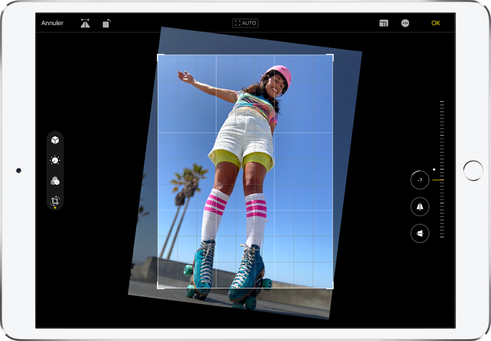 L’iPad en orientation paysage. Au centre de l’écran se trouve une photo en mode édition avec une grille en superposition et un cadre pour recadrer l’image. Sur le côté gauche de l’écran, le bouton Recadrer est sélectionné. Sur le côté droit de l’écran se trouvent les options d’amélioration de la géométrie. L’option Redresser est sélectionnée et le curseur d’intensité est réglé à -5.