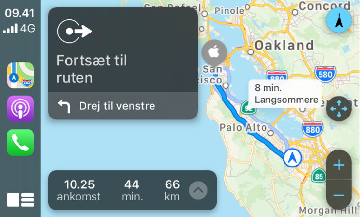 CarPlay, der viser symboler for Kort, Podcasts og Telefon til venstre, kortet til en kørerute til højre inklusive zoomknapper,drejeinstruktion og oplysninger om forventet ankomst.