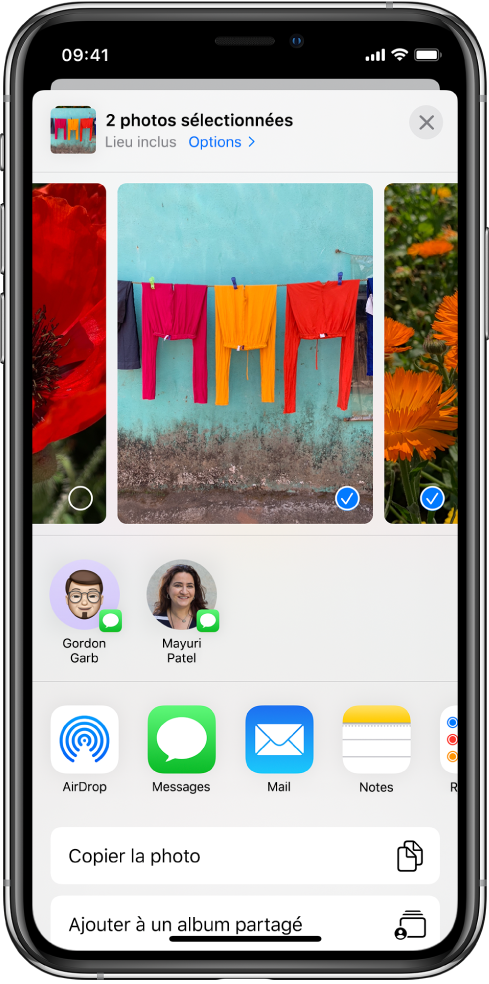 L’écran Partage avec des photos affichées en haut ; deux d’entre elles sont sélectionnées, comme indiqué par la coche blanche dans un rond bleu. Le rang sous les photos présente les amis avec lesquels vous pouvez les partager à l’aide d’AirDrop. D’autres options de partage sont proposées en dessous, notamment, de gauche à droite : Messages, Mail, Albums partagés et Ajouter à Notes. Le rang du bas contient les boutons suivants : Copier, Copier le lien iCloud, Diaporama, AirPlay, et Ajouter à un album.