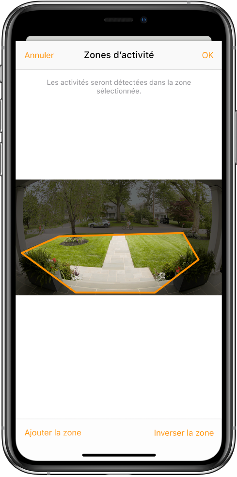 Écran d’iPhone montrant une zone d’activité dans une image prise par une caméra de porte. La zone d’activité inclut un perron et une allée, mais exclut la rue et la voie d’accès. Les boutons Annuler et OK se trouvent au-dessus de l’image. Les boutons « Ajouter la zone » et « Inverser la zone » se trouvent en dessous.