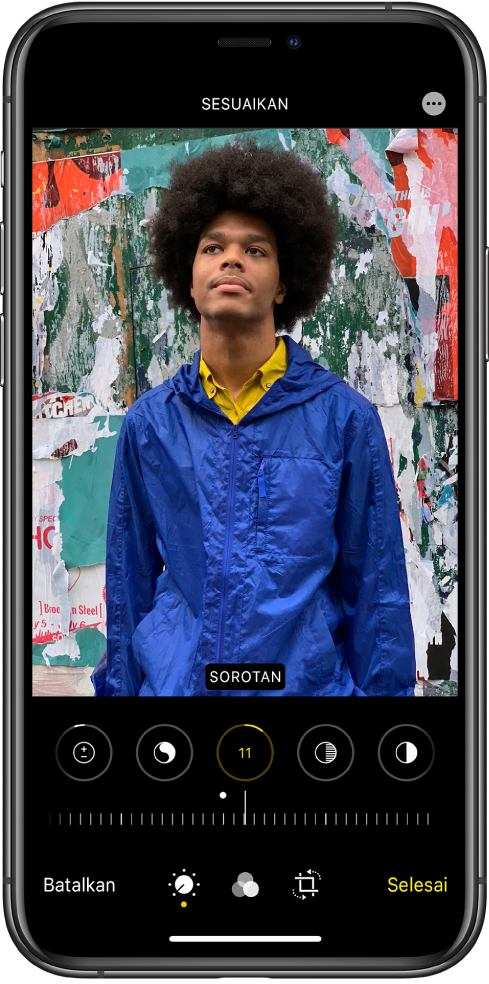 Layar edit dengan foto di tengah. Di bawah foto terdapat tombol pengeditan untuk Sorot, Bayangan, Kecerahan, Titik Hitam, dan Saturasi. Kecerahan dipilih. Di bawah tombol pengeditan terdapat penggeser untuk menyesuaikan level Kecerahan. Di bawah penggeser, dari kiri ke kanan adalah tombol Batalkan, Edit, Filter, Potong, dan Selesai. Tombol Pilihan Lainnya terdapat di pojok kanan atas.