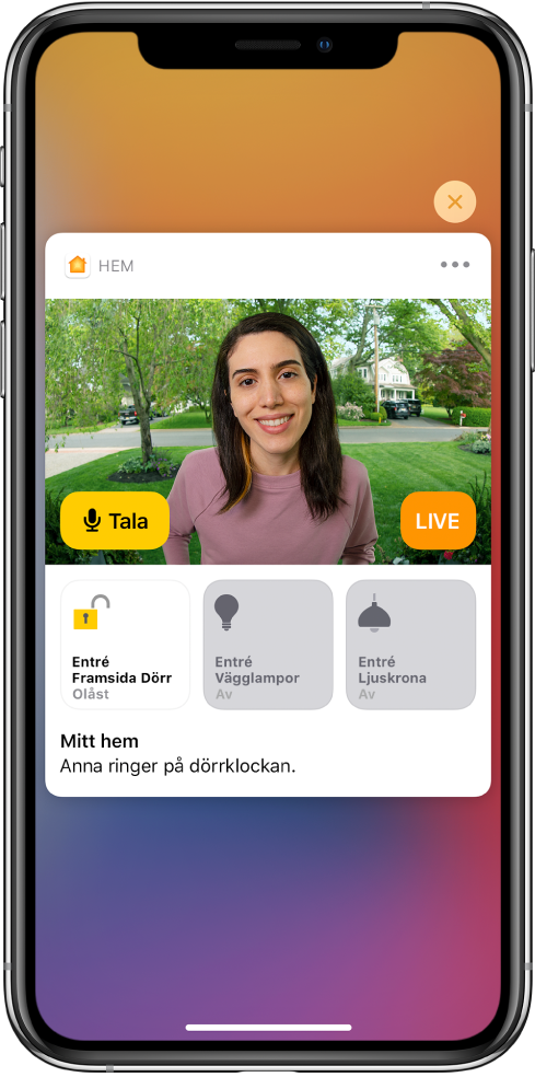 En notis från Hem visas på iPhone-skärmen. Den visar bilden på en person vid ytterdörren. Till vänster finns knappen Tala. Under det finns tillbehörsknappar för ytterdörren och entréljus. Orden ”Ashley ringer på dörrklockan”. Högst upp till höger på notisen finns en stängningsknapp.