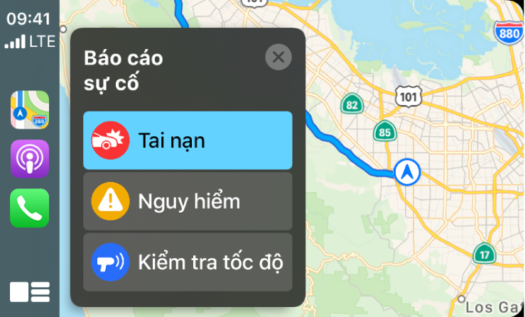 CarPlay đang hiển thị các biểu tượng cho Bản đồ, Podcast và Điện thoại ở bên trái và một bản đồ của khu vực hiện tại ở bên phải đang báo Tai nạn giao thông, Nguy hiểm hoặc Kiểm tra tốc độ.