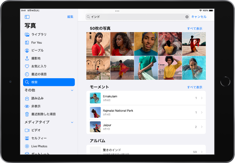 写真が横向きに開いています。画面の左側にあるサイドバーには、「写真」、「For You」、「アルバム」、および「検索」ボタンがあり、「検索」が選択されています。画面の上部には検索フィールドがあり、場所と日付が入力されています。検索フィールドの下に、候補の検索結果のリストが表示されています。検索用語から得られた写真のグリッドが画面の中央にあります。写真のグリッドの左上には検索結果の合計の写真数が表示されています。写真のグリッドの右上には「すべて表示」ボタンがあります。