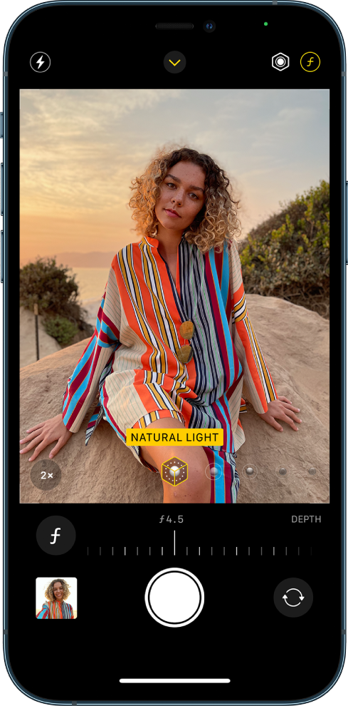 Екранът на Camera (Камера) в режим Portrait (Портрет). Избран е бутонът Depth Adjustment (Настройване на дълбочина на рязкост) в горния десен ъгъл на екрана. Във визьора на камерата полето показва, че функцията Portrait Lighting (Портретно осветление) е настроена на Natural Light (Естествено осветление), а плъзгачът може да се изтегли, за да се промени осветлението. Под визьора има плъзгач за настройване на Depth Control (Дълбочина на рязкост),