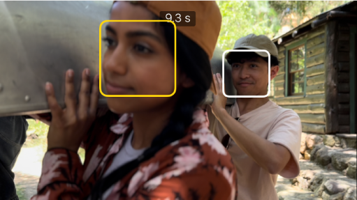 Un clip en mode de cine al visor, amb un quadre groc sòlid al voltant d'una cara que indica que el focus s'ha bloquejat en aquell objecte. Apareix un quadre blanc en un objecte que no està enfocat.