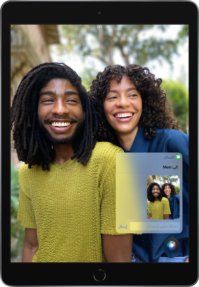 تطبيق الصور مفتوح وتظهر به صورة لشخصين. في الجزء العلوي من الصورة رسالة موجهة إلى أمي، والتي تتضمن نفس الصورة. يظهر Siri في أسفل الشاشة.