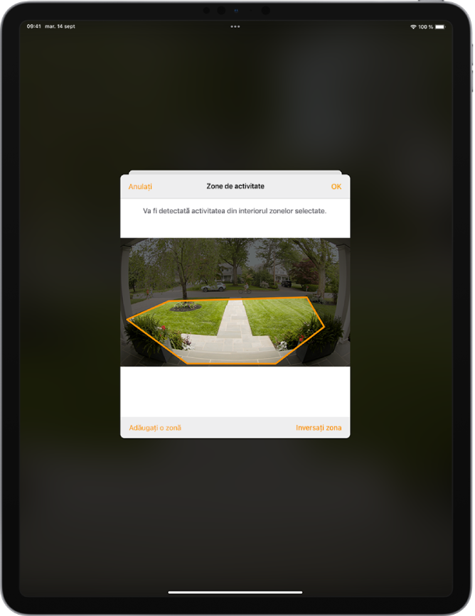 Ecranul iPad-ului, afișând o zonă de activitate în cadrul unei imagini înregistrate de camera soneriei de intrare. Zona de activitate include veranda din față și aleea de intrare, dar exclude strada și drumul privat. Butoanele Anulați și OK se află deasupra imaginii. Butoanele Adăugați o zonă și Inversați zona sunt dedesubt.