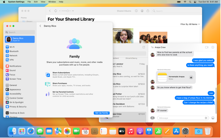 El escritorio de la Mac con varias ventanas abiertas: el panel Configuración del Sistema muestra el panel de configuración Compartir en familia, Fotos muestra una Fototeca compartida de iCloud, y la ventana Mensajes muestra una conversación que incluye una nota del grupo en que se está colaborando.