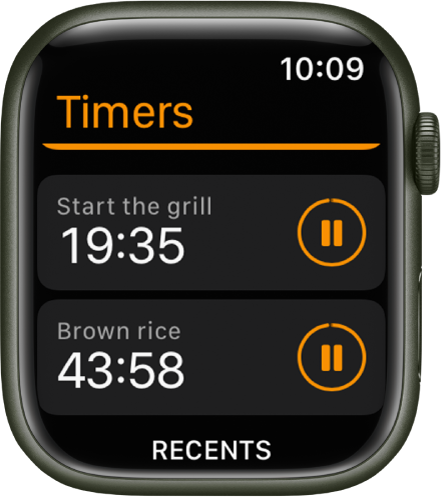 Dva časovnika v aplikaciji Timers (Časovniki). Časovnik imenovan »Start the grill« (Vključi žar) je blizu vrha. Spodaj je časovnik imenovan »Brown rice« (Rjavi riž). Vsak časovnik prikazuje preostali čas pod imenom časovnika in gumb za premor na desni. Na dnu zaslona je gumb Recents (Nedavno).