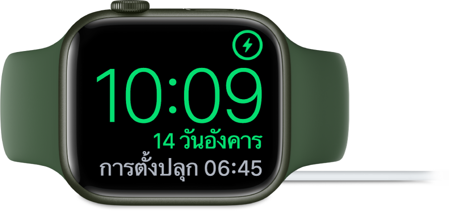 Apple Watch ที่วางตะแคง และเชื่อมต่ออยู่กับที่ชาร์จ โดยหน้าจอแสดงสัญลักษณ์การชาร์จตรงมุมขวาบนสุด เวลาปัจจุบันอยู่ด้านล่างสัญลักษณ์การชาร์จ และเวลาของการตั้งปลุกครั้งต่อไป