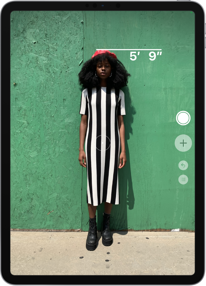 A person’s height is measured, with the height measurement showing at the top of the person’s head. The Take Picture button is active on the right edge for taking a picture of the measurement. The green Camera In Use indicator appears at the top right.