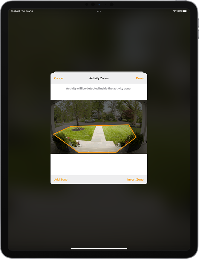 Na zaslonu iPada je prikazano območje dejavnosti znotraj slike, ki jo je zajela kamera hišnega zvonca. Območje dejavnosti zajema verando in pot do vrat, vendar ne vključuje ulice in dovoza. Nad sliko sta gumba Cancel in Done. Spodaj sta gumba Add Zone in Invert Zone.