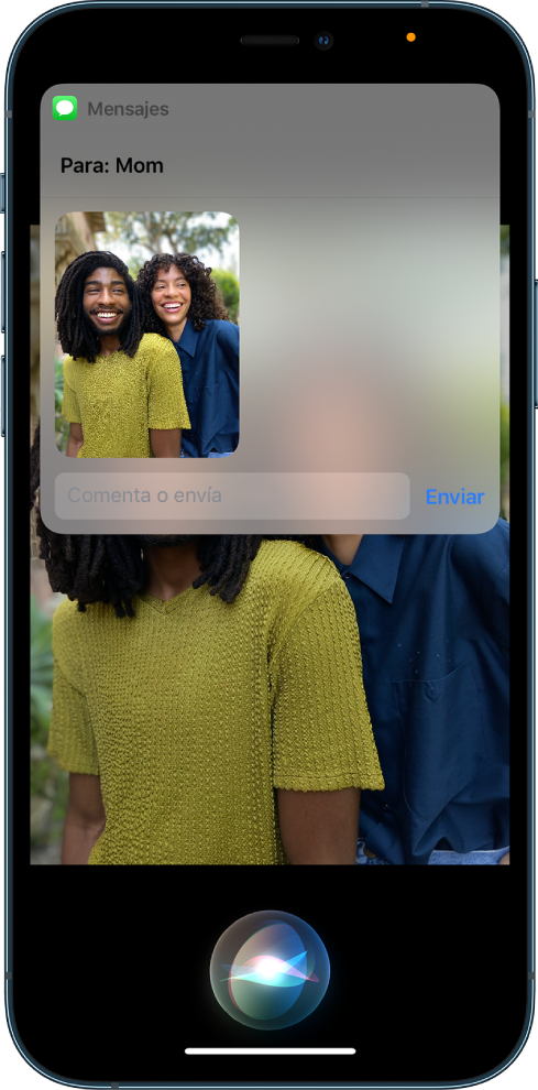 L’app Fotos oberta amb una foto de dues persones. A la part superior de la foto hi ha un missatge adreçat a Mamà, que inclou la mateixa foto. Siri es mostra a la part inferior de la pantalla.
