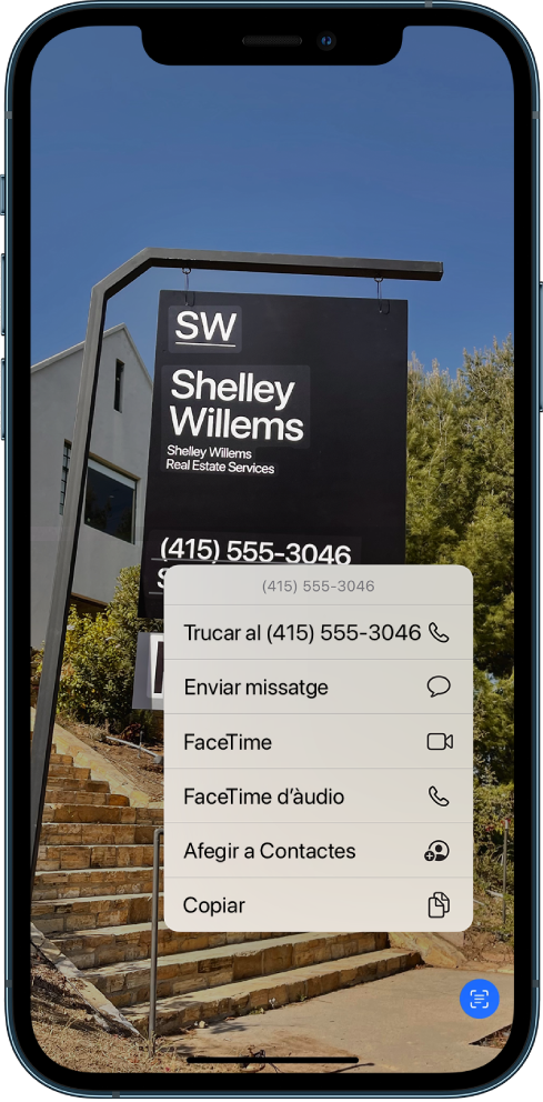 Hi ha una foto oberta que ocupa tota la pantalla. A la foto hi ha un signe que inclou text i un número de telèfon. El número de telèfon està seleccionat i a la pantalla hi ha disponibles les opcions següents: Trucar, “Enviar missatge”, FaceTime, “FaceTime d’àudio”, “Afegir als contactes” i Copiar.