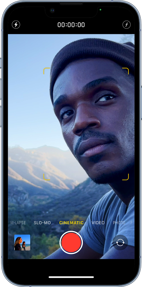 Camera screen in Cinematic video mode. The background and foreground are blurred. At the top of the screen are, from left to right, the Flash button, the recording timer, and the Depth Control button. At the bottom of the screen are, from left to right, the Photo and Video Viewer button, the Record button, and the Camera Chooser Back-Facing button.
